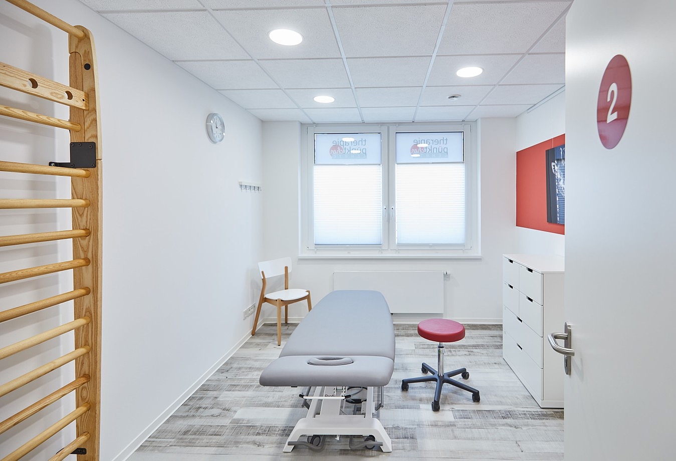 Bahendlungszimmer mit Therapieliege und Sprossenwand auf der linken Seite