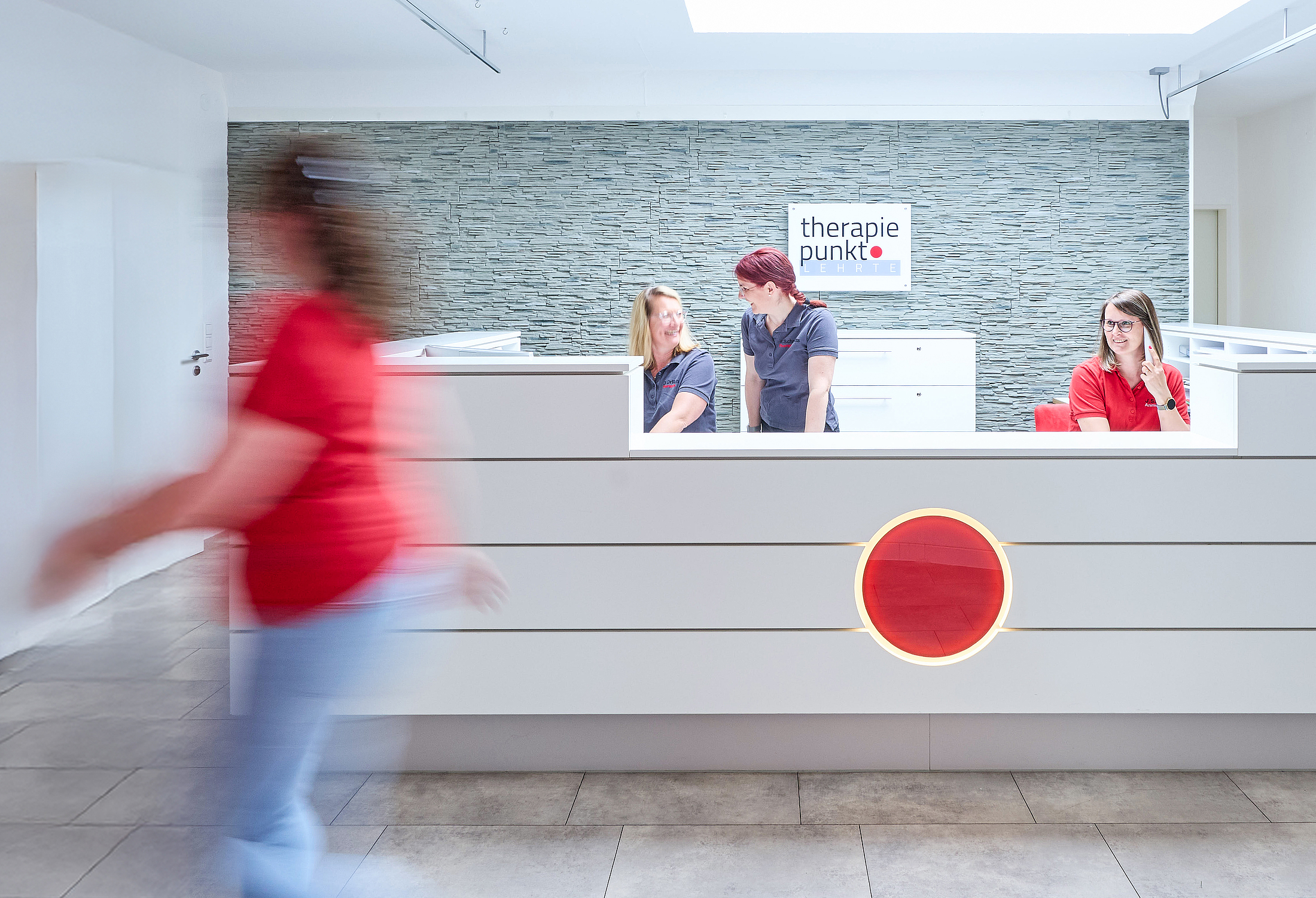 Empfangstresen der Praxis Therapiepunkt in Lehrte, drei Personen hinter dem Tresen