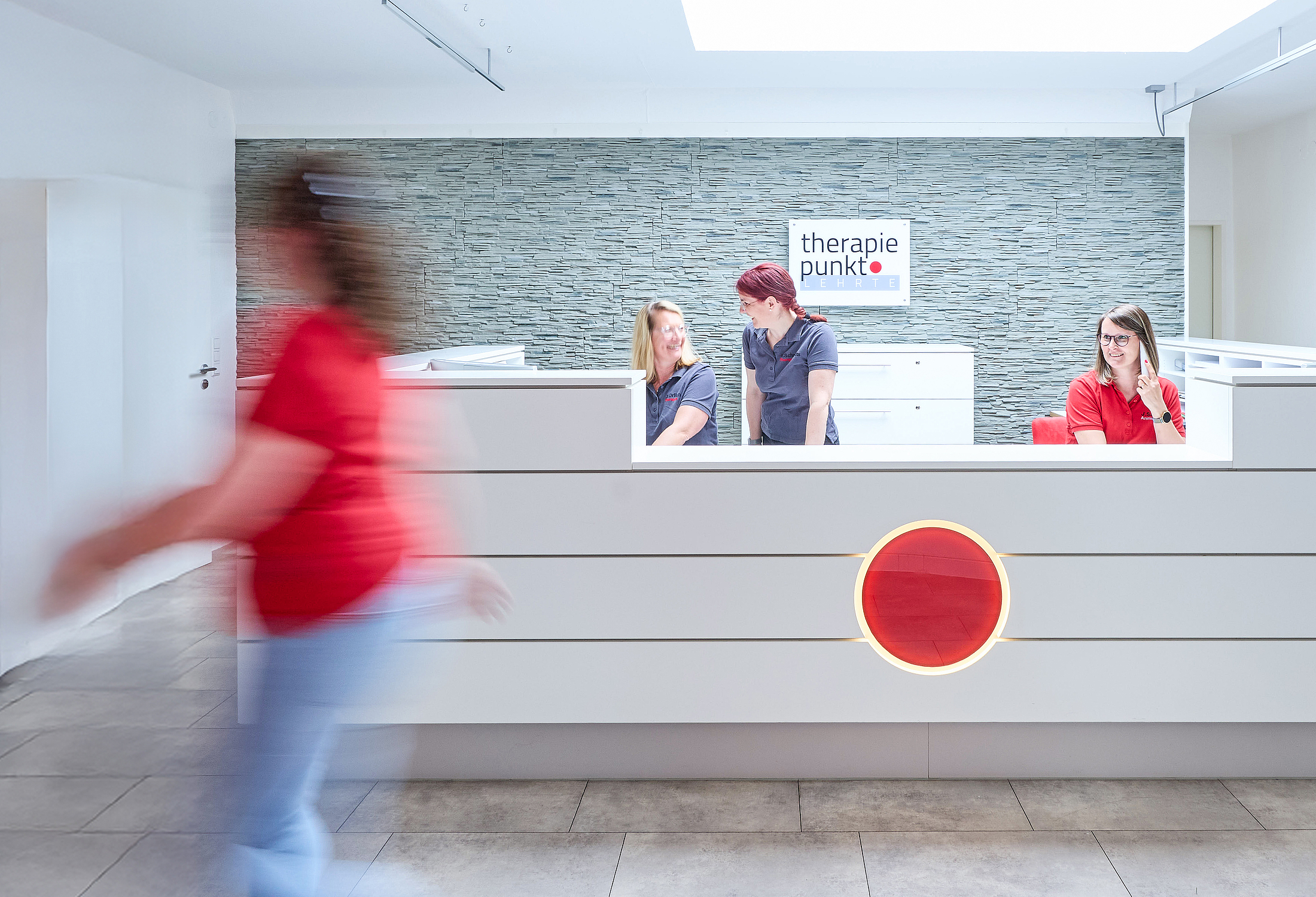 Empfangstresen der Praxis Therapiepunkt in Lehrte, drei Personen hinter dem Tresen