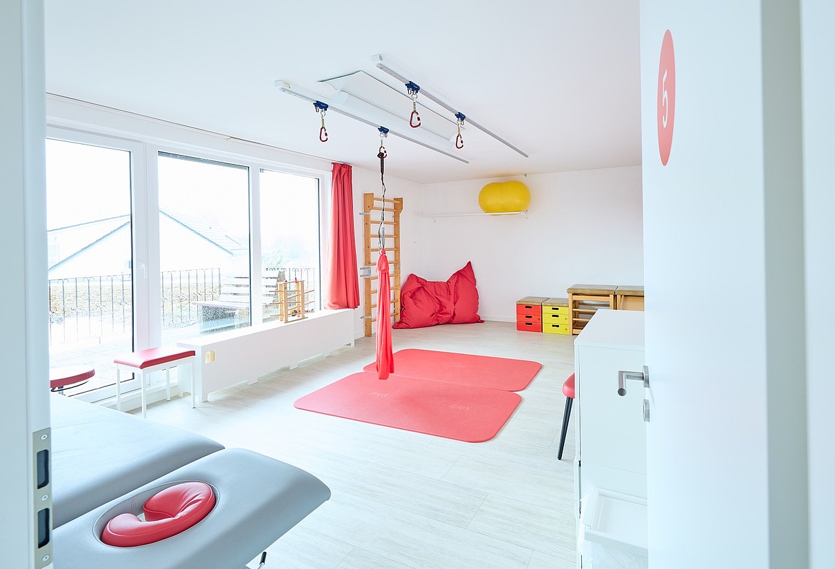 heller Therapieraum mit roter Matte auf dem Boden, 