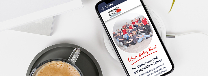 Ansicht eines Smartphones mit der neuen Therapiepunkt-Website, daneben Kaffetasse